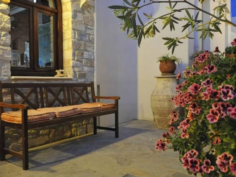 a wooden bench placed in front of a house , surrounded by potted plants and flowers at Paliomylos Spa Hotel