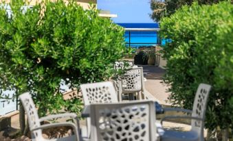 a row of white chairs is set up in a garden with greenery and a view of the ocean at Joseph Charles