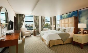 a large , well - decorated hotel room with a king - sized bed , a couch , and a tv . also a dining table in the at Hilton Windhoek