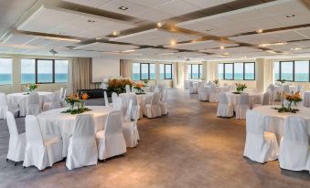 a large , empty banquet hall with white tables and chairs set up for an event at Grand Mercure Recife Boa Viagem