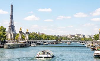 a boat is sailing on a river near the eiffel tower in paris , france , under a blue sky at Ibis Styles Paris Romainville