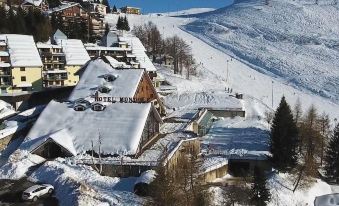 a snow - covered ski resort with multiple buildings , some of which have ski slopes and others on skiers at Hotel Mondole