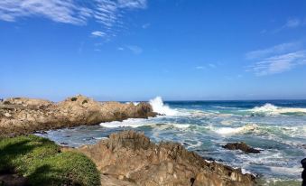 a rocky shoreline with waves crashing against the rocks , creating a serene and picturesque scene at The Olympia Lodge