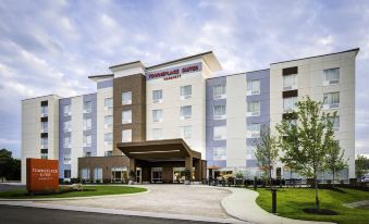 a large , modern hotel with a red and white facade and multiple floors , situated on a street at TownePlace Suites Mobile Saraland