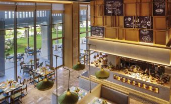 a modern restaurant with an open kitchen and dining area , featuring a variety of seating options at Movenpick Resort Cam Ranh