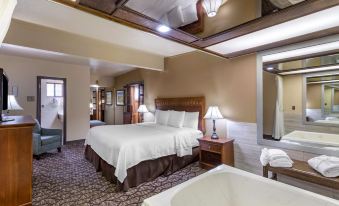 a large bed with white linens is in a room with a bathtub and lamps at Best Western Dunmar Inn