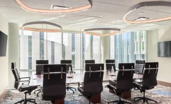 a modern conference room with multiple chairs arranged around a long table , and large windows providing natural light at The Civic Hotel