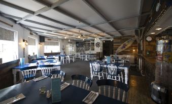 a large dining room with multiple tables and chairs , some of which are covered in blue tablecloths at Parsonage Farm Inn