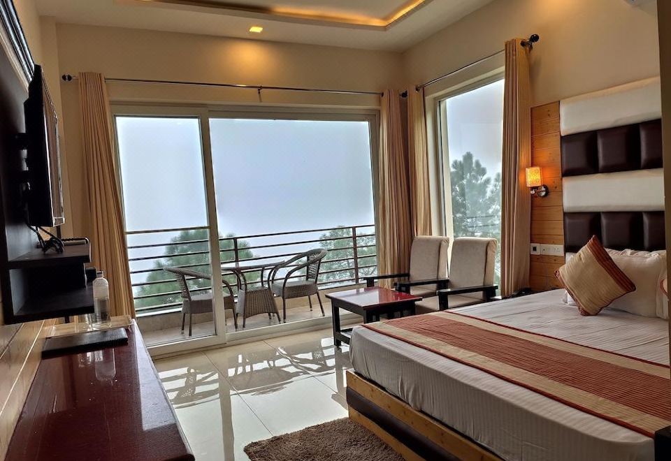 a large bedroom with a king - sized bed and a balcony overlooking a beautiful view of the ocean at Wood Stock Kasauli - Rooms & Cottages - Panoramic View & Balcony Rooms