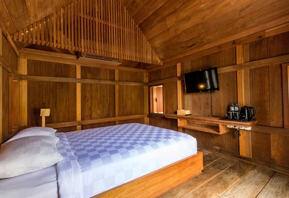 a bedroom with a wooden bed and a tv mounted on the wall , surrounded by wooden walls at Berugo Cottage