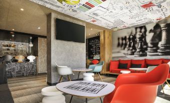 a modern office space with various seating options , including couches , chairs , and a dining table at Ibis Lyon Villefranche-Sur-Saône