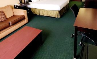 a hotel room with a bed , couch , coffee table , and other amenities on the carpeted floor at Executive Inn