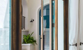 a room with a glass door and white walls , leading to a balcony with plants at Santarena Hotel at Las Catalinas