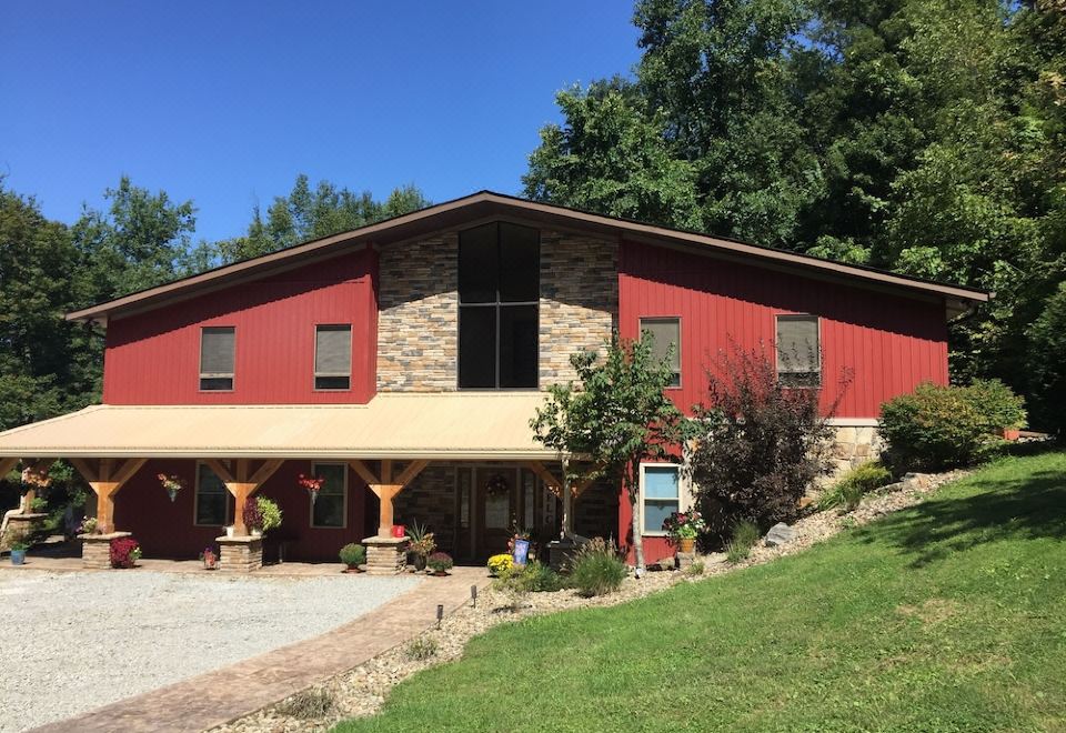 a red brick building with a stone foundation and large windows is surrounded by green grass and trees at Seams Like Home B&B