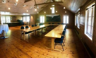 a large , wooden conference room with multiple tables and chairs arranged for a meeting or event at Byrkjedalstunet Hotell