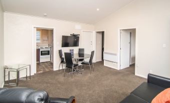 a modern apartment with a living room , dining area , and kitchen , all connected by a large window at Cedar Lodge Motel