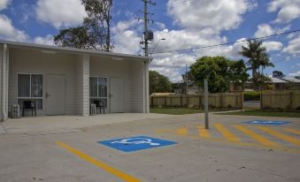 a parking lot with a car parked in the middle and a building on the side at Kallangur Motel