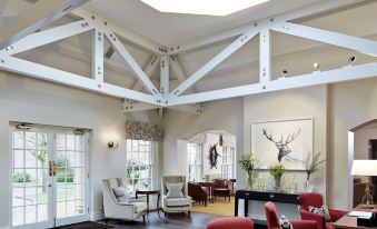 a spacious living room with high ceilings , large windows , and red chairs , under a white skylight at The Woburn