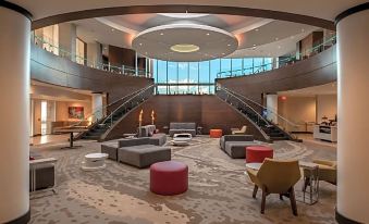 a modern , spacious lobby with multiple seating areas and large windows offering views of the city at Hilton Garden Inn Dallas - at Hurst Conference Center