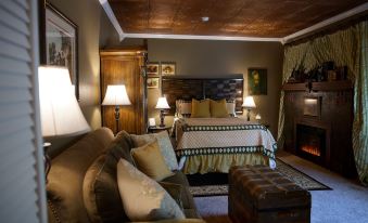 a cozy bedroom with a large bed , a couch , and a fireplace , decorated with pictures on the wall at Fiddler's Inn