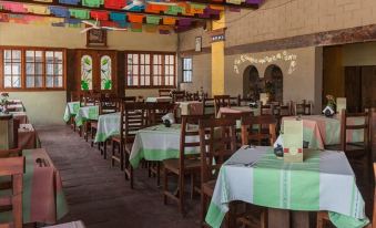 a restaurant with wooden tables and chairs , green tablecloths , and colorful decorations on the ceiling at Donaji