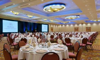 a large conference room with multiple tables and chairs , all set for a formal event at Hilton Vancouver Washington