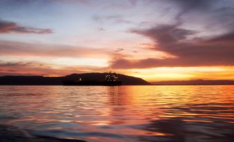 a sunset over a body of water with mountains in the background , creating a serene and picturesque scene at Grand Hotel Excelsior Port Royal