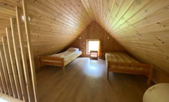 a wooden attic room with three beds , one on the left , one in the middle , and one on the right at Hörgsland Cottages
