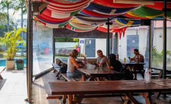 a group of people sitting at a picnic table in a restaurant , enjoying each other 's company at Brisbane Backpackers Resort