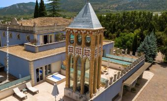 a large , multi - leveled villa with a blue roof and a pool is situated in the mountains at Hotel Ferrero
