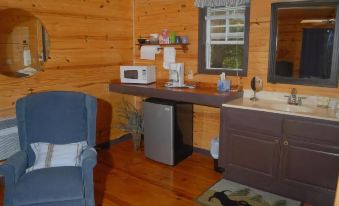 a small wooden cabin with a microwave , microwave on a shelf , and a dining table in the corner at River Valley Rentals