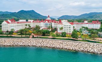 "A large building with the name ""resort"" on it overlooks the water in front" at Hong Kong Disneyland Hotel