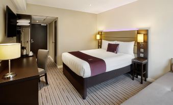 a large bed with a purple blanket is in the middle of a room with a striped rug at Premier Inn Felixstowe Town Centre