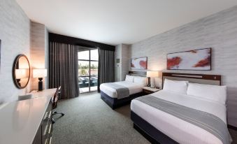 a hotel room with two beds , a desk , and a window , all decorated in a modern style at Delta Downs Racetrack Casino Hotel