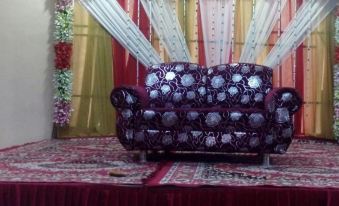 a luxurious stage with a purple chair , gold and white curtains , and flowers on the stage at Hotel International