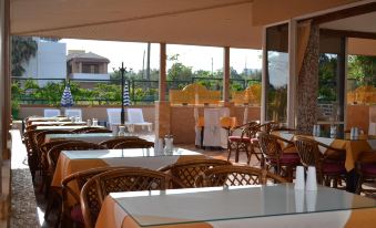 a restaurant with several tables and chairs , some of which are covered in orange tablecloths at Palladion