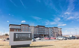 a large hotel building with a parking lot in front of it , under a clear blue sky at Staybridge Suites Denver North - Thornton