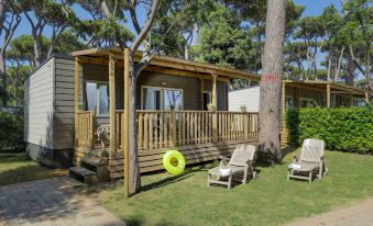 a wooden house with a deck , lounge chairs , and a yellow donut on the grass at Hu Montescudaio Village