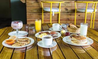 a wooden dining table with a variety of breakfast foods , including pancakes , fruit , and beverages at Puerto Barillas