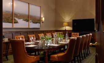 a dining room with a large oval table surrounded by chairs , all set for a meal at Ballynahinch Castle Hotel