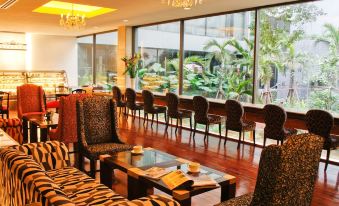 The restaurant features large windows, tables in the middle, and an area rug at Ambassador Hotel Bangkok