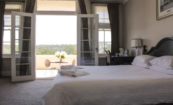 a bedroom with a large bed and white linens , leading to a balcony with sliding glass doors at Wallacia Hotel