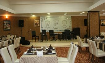 a dining room with several tables and chairs , as well as a stage set up for an event at Sword Hotel