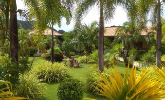a lush tropical garden with palm trees , grass , and various plants , as well as people enjoying the scenery at Stella Resort