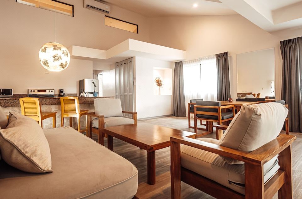 a modern living room with wooden furniture , including a couch , chairs , and a dining table at Bahia del Sol Beach Front Boutique Hotel