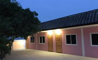 a pink building with wooden doors and a black roof , lit by lights at night at Smile Resort