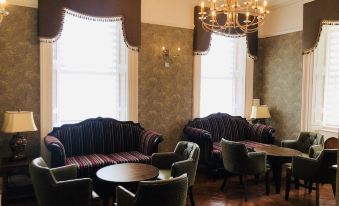 a room with two couches , a dining table , chairs , and a chandelier hanging from the ceiling at Kilmorey Arms Hotel