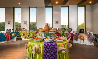 a dining room with a large table set for a party , filled with colorful food and drinks at Hotel Waya Guajira