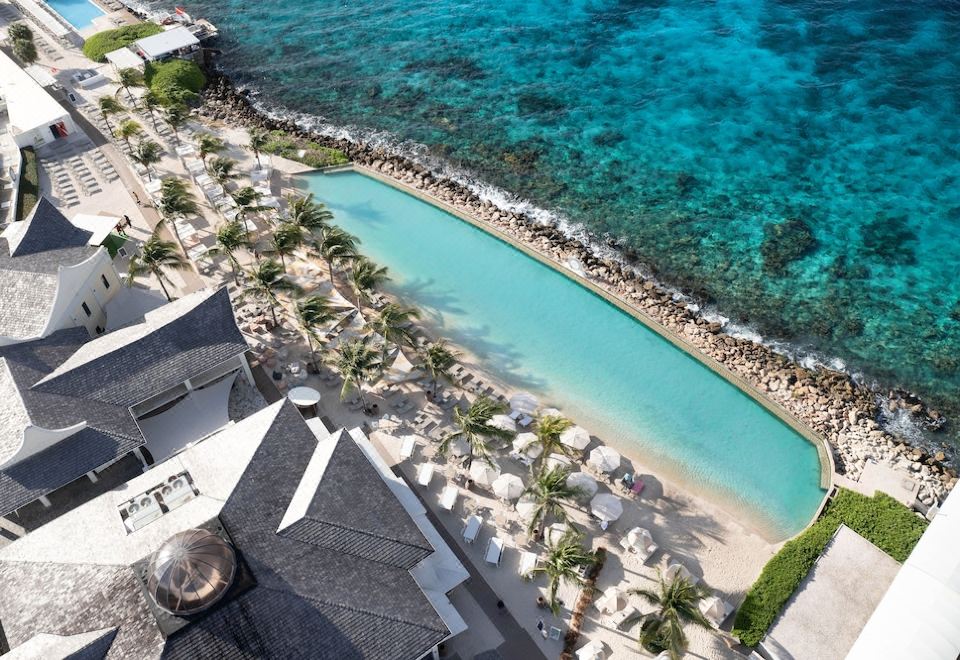 aerial view of a tropical beach resort with a large pool surrounded by white sand and palm trees at Papagayo Beach Resort