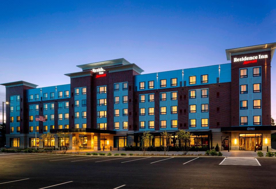a modern hotel building with multiple floors , surrounded by trees and parking lots at dusk at Residence Inn Bangor